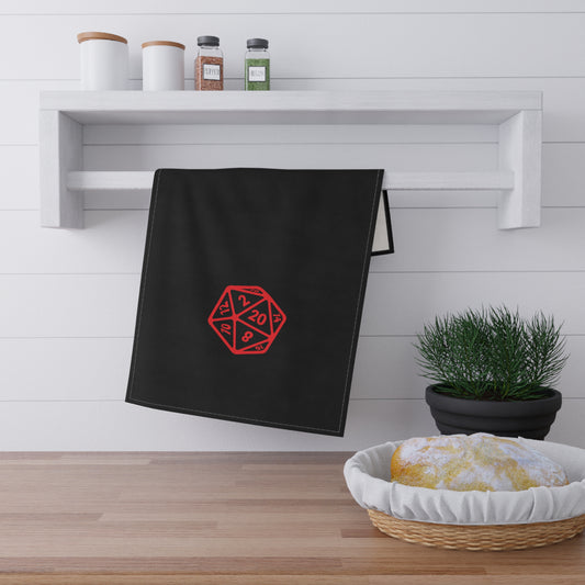 Black towel with red geometric design hanging on a white wall above a wooden surface with a basket of bread and a plant.