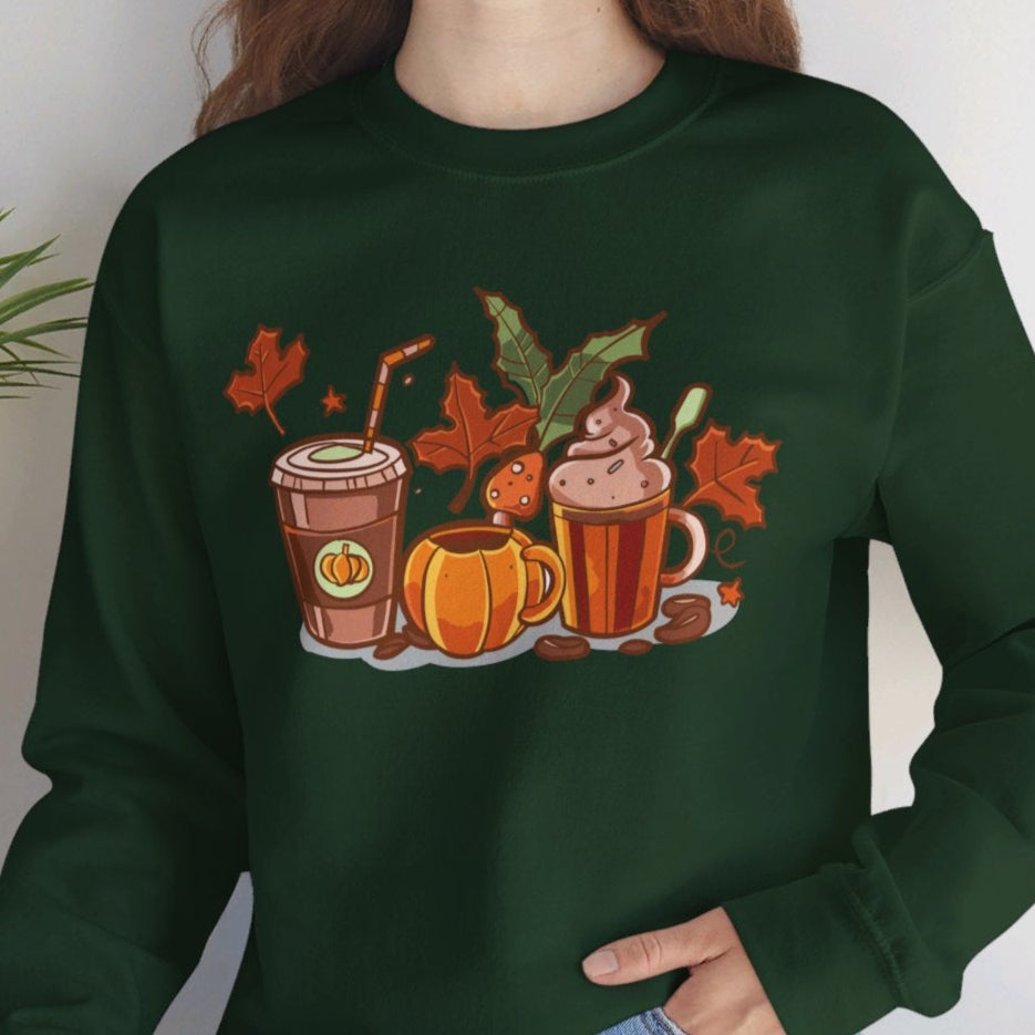 A woman sitting and smiling, wearing a green sweatshirt with a graphic of pumpkin spice lattes and autumn leaves.