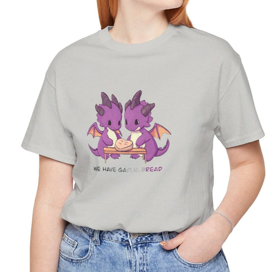 Person wearing a gray t-shirt with cartoon dragons making garlic bread and text, standing against a white background