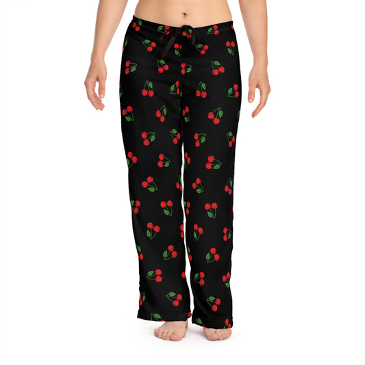 Black pajama pants with cherry pattern worn by a person on a white background