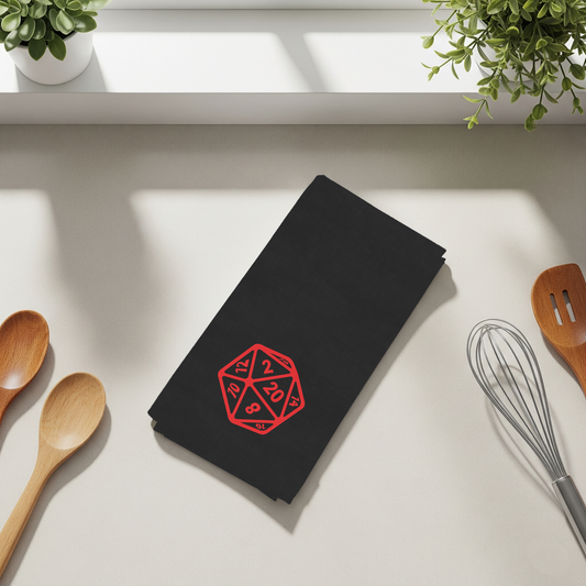 Black towel with red dice design on a kitchen counter with utensils and plants.