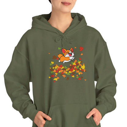 A woman wearing a green hoodie with a graphic of a corgi dog surrounded by autumn leaves.