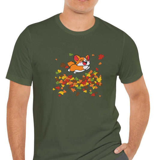 Male presenting person wearing a green t-shirt with a cartoon corgi playing in all leaves.